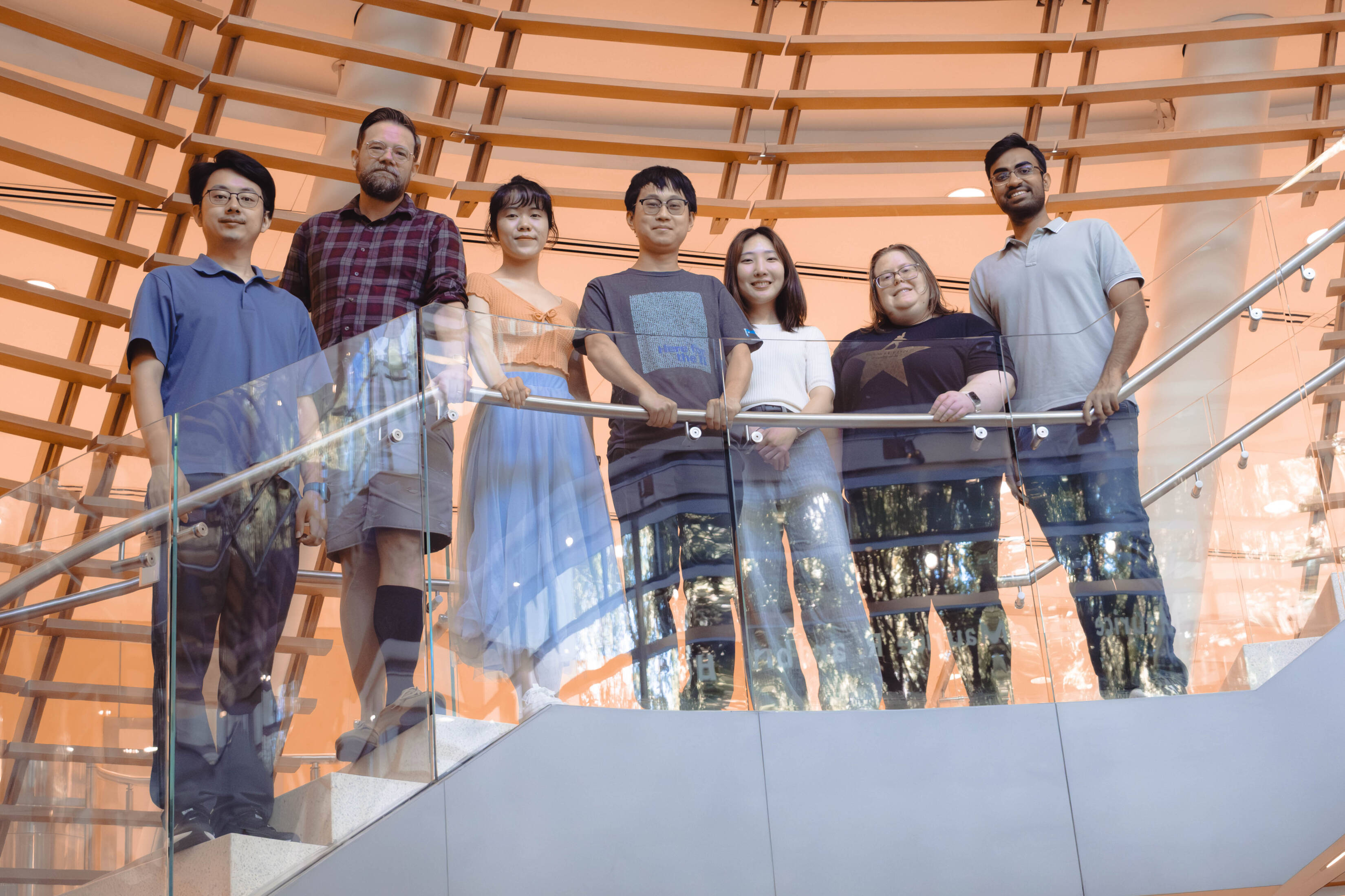 Journal Club organizers standing on a staircase landing, from left to right: Hengrui Liu, Keith Hamilton, Yixin Hu, Charles Xu, Yoonji Kim, Kimberly Elicker, and Dhyey Gandhi (Credit: Lori Chertoff)
