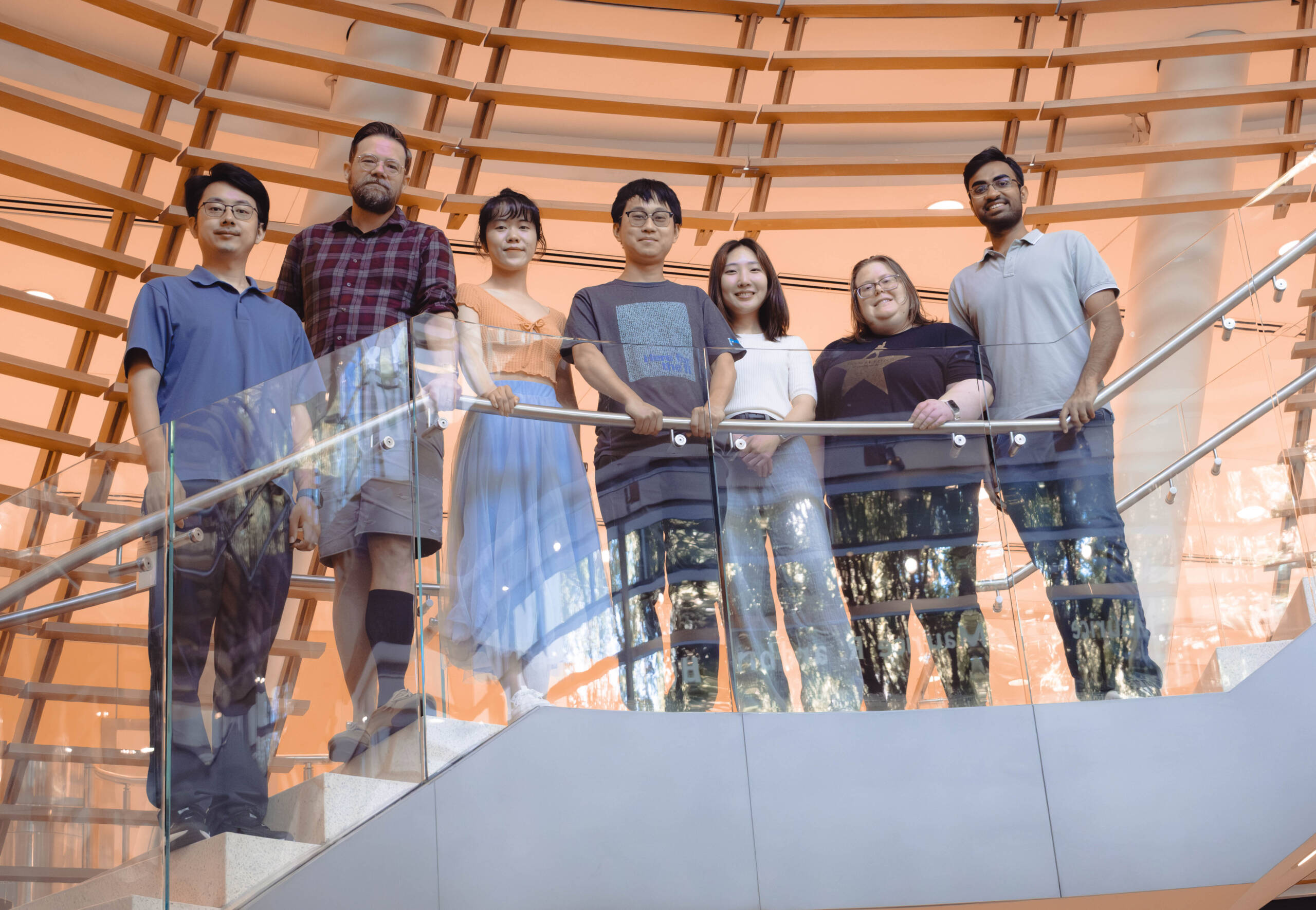 Journal Club organizers standing on a staircase landing, from left to right: Hengrui Liu, Keith Hamilton, Yixin Hu, Charles Xu, Yoonji Kim, Kimberly Elicker, and Dhyey Gandhi (Credit: Lori Chertoff)