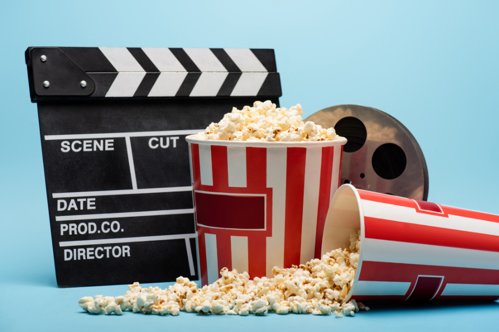 A clapper board bucket of popcorn and film reel on a blue background
