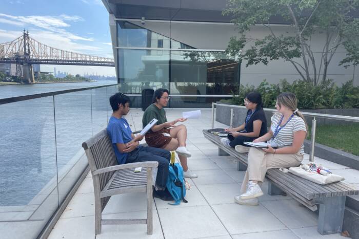 A mentor and three students in a journal club discussion outdoors.