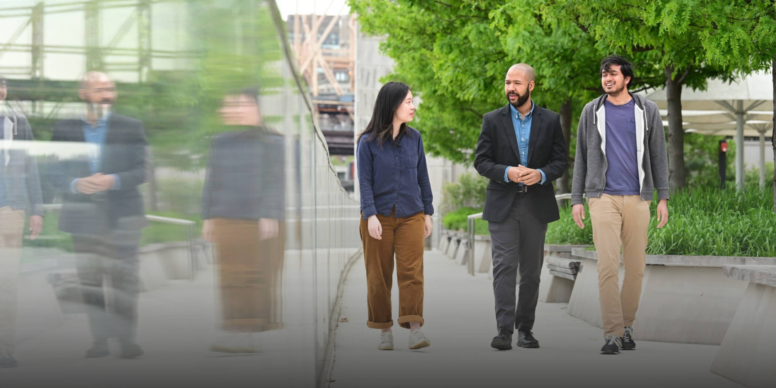 three community members walking on a campus sidewalk